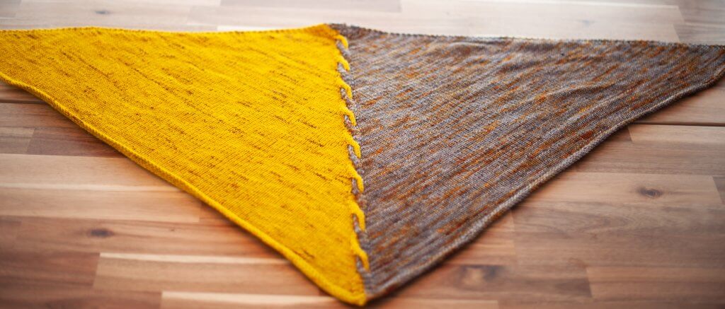 The Edge of Winter Shawl: a triangular shawl laying flat on a table.