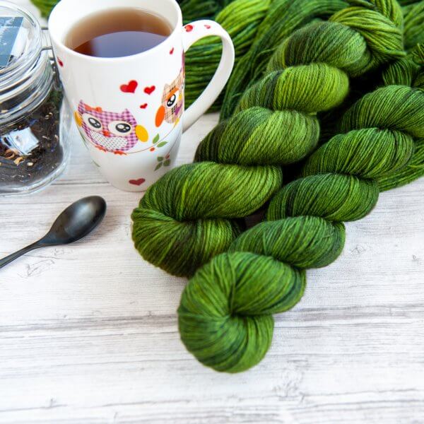 two skeins of yarn in the colorway 'Nessie' next to a cup of tea