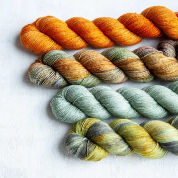 Four skeins in the following colorways: Heilan Coo (orange), Barrowland Ballroom (variegated), Portree Harbour (pale blue-green), Kilchurn Castle (green and grey with golden speckles)