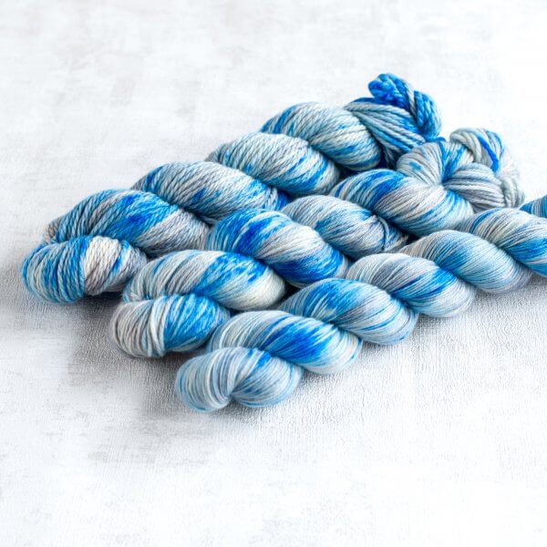 three skeins of silver yarn with blue speckles
